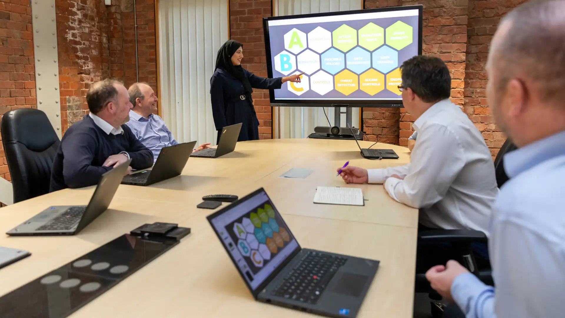 A professional woman presenting on a large screen displaying a hexagonal diagram 1